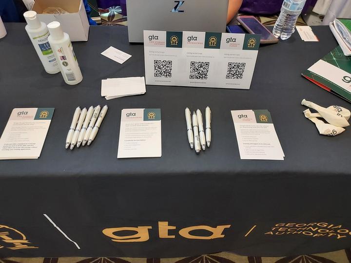 Photo of a table with product marketing materials and a GTA tablecloth.