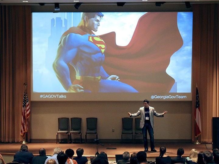 Nikhil on stage with Superman on the presentation screen