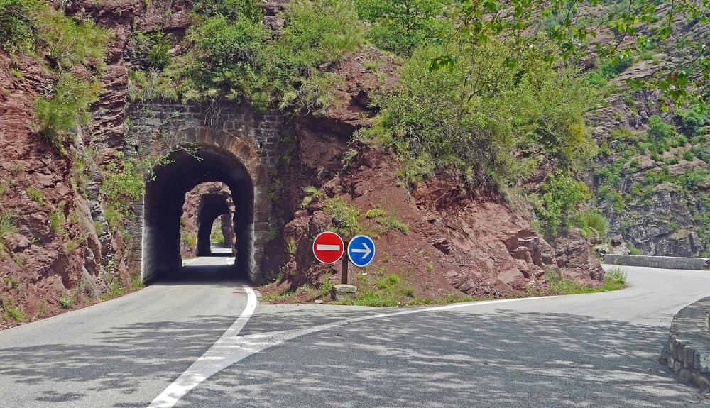 A highway that splits into two directions around the edge of a mountain foothill.