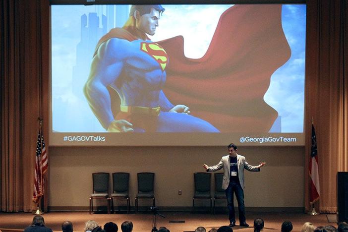 Nikhil on stage with Superman on the presentation screen